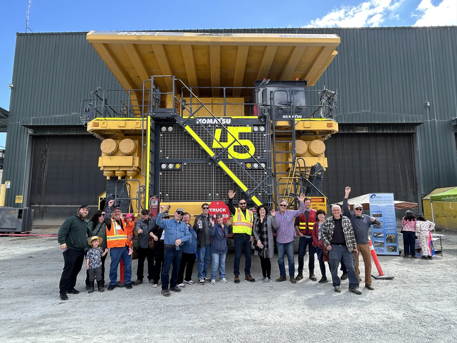 group of people standing in front of a dump truck